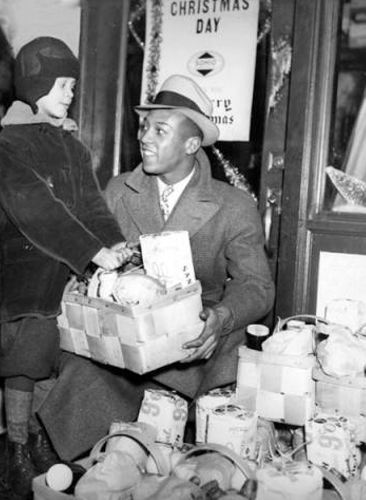 1935: Jesse Owens brings Christmas gift baskets to needy families.
