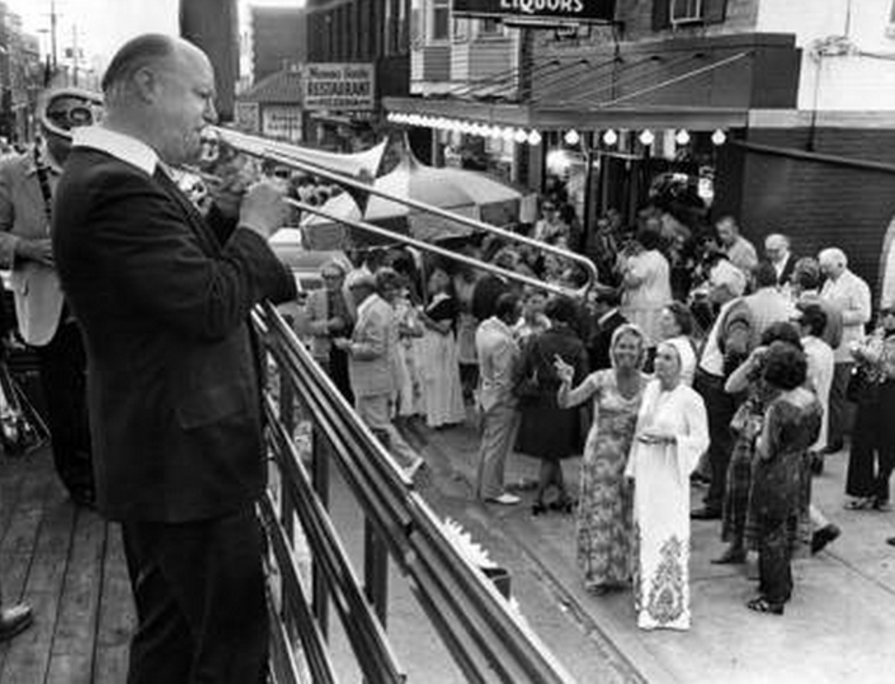 A crowd gathers to hear a musician play outside of Guarino's restaurant, 1975.