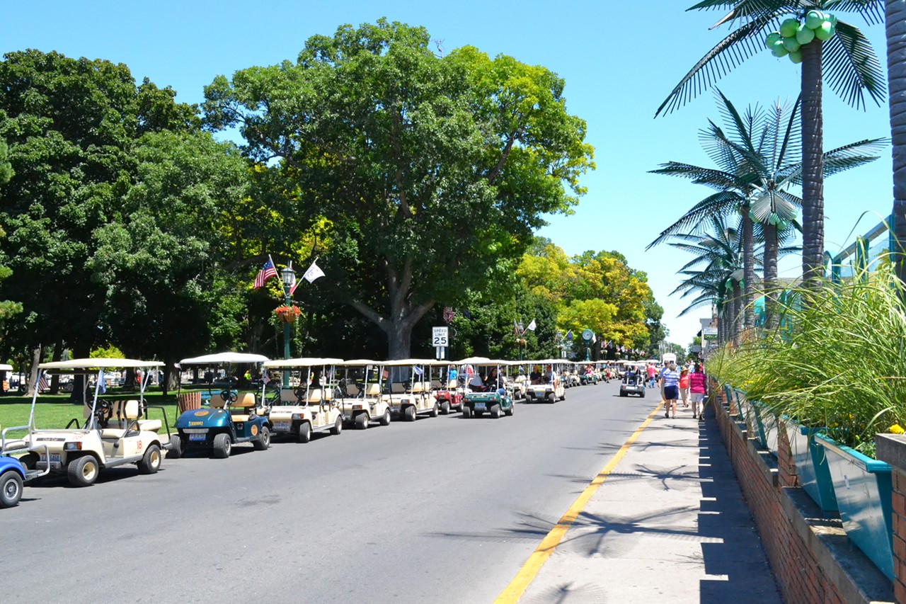 Rented golf carts and fake palm trees line street.