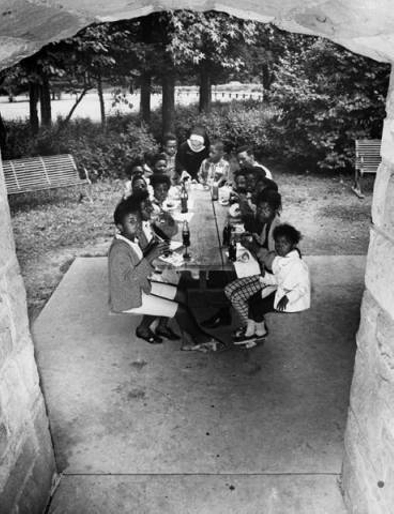 Lunch time and a scenic view for neighborhood youngsters at Oak Grove Picnic Area, Brecksville Reservation. Sister Clarita is assisting. 1968