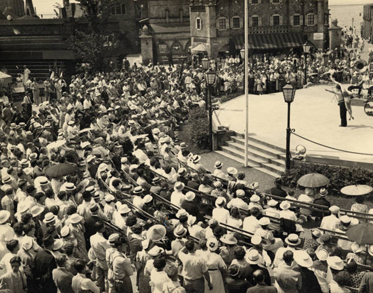 An audience watches a performance at Streets of the World. The Streets of the World attraction at the Great Lakes Exposition featured shopping, dining, and scenery representative of the following cultures: African, Armenian, Austrian, Belgian, Chinese, Croatian, Czech, Danish, Dutch, English, French, German, Greek, Hindu, Hungarian, Irish, Italian, Japanese, Jewish, Latvian, Lithuanian, Manx, Mexican, Norwegian, Polish, Rusin, Russian, Romanian, Scotch, Serbian, Slovak, Slovene, Spanish, Swedish, Swiss, Syrian, Ukrainian and Welsh. Streets of the World paid tribute to Cleveland's immigrant heritage and enabled visitors to experience a variety of cultures.