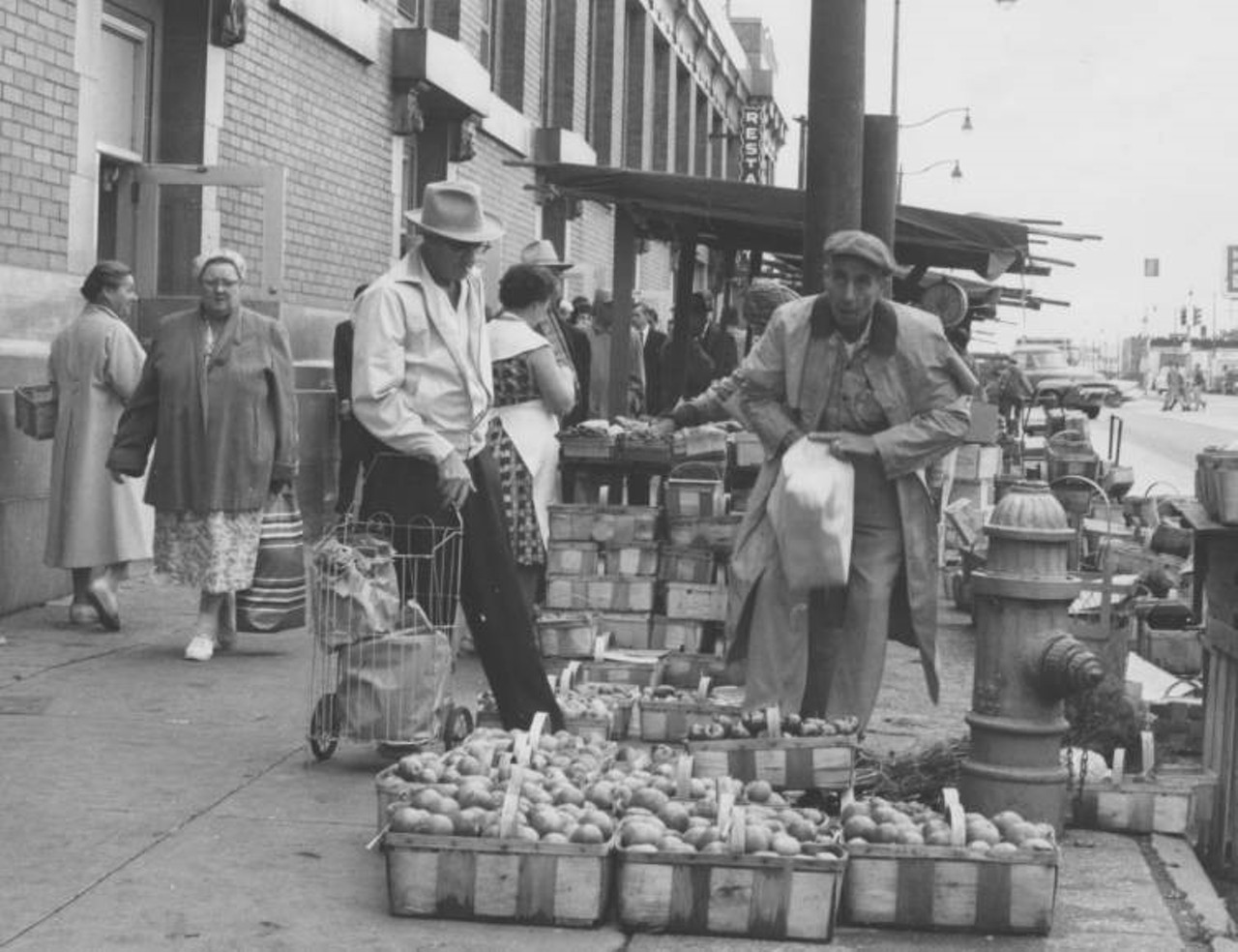 View of shoppers and outdoor produce stall along sidewalk on Lorain Avenue. The photo was taken September 30, 1962 in connection with the fiftieth anniversary of the market.