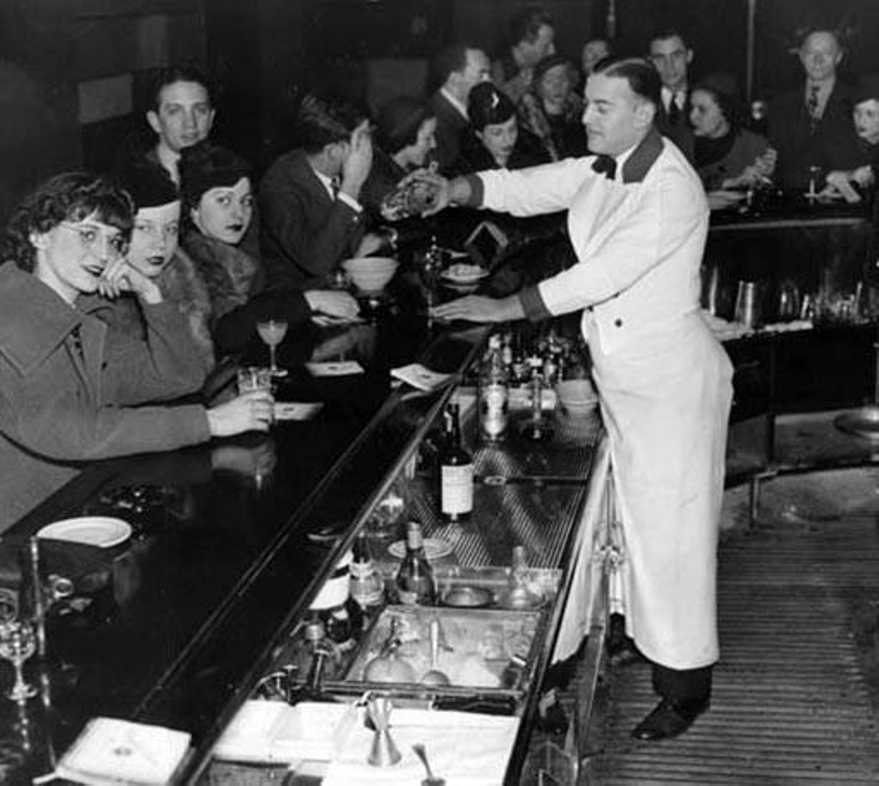 Bartender serves up specials at the Mayfair Casino bar. Here, folks could partake in the Five O'Clock Penny Club special -- a version of "happy hour" where patrons could order up drinks for a penny,  1937.