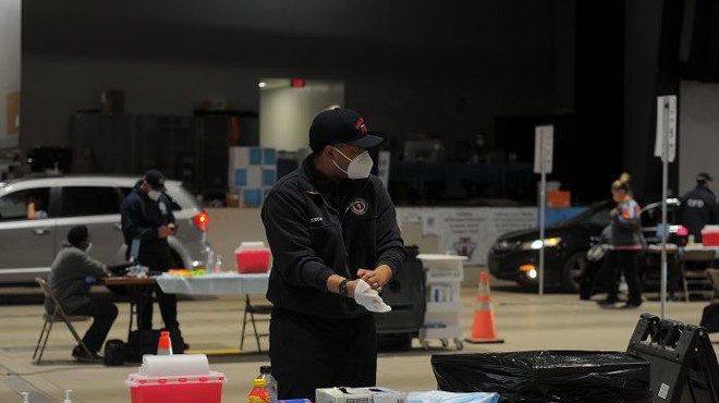 A Columbus Fire Department member dons gloves while working at a mass vaccination site at the Celeste Center in Columbus