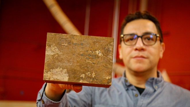 Armando Cañas, head of construction at Redhouse Studio, holds up a brick of building material made from mushrooms.