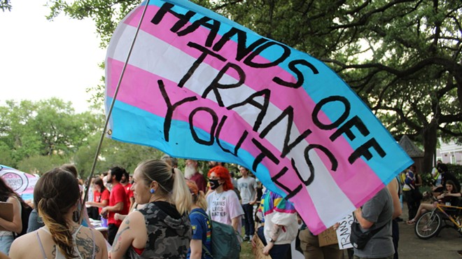 A transgender Pride flag is covered with the words “Hands Off Trans Youth.”