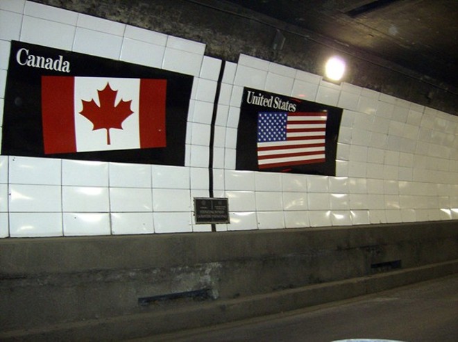 Flags of Canada and the United States over a metal boundary marker in the Detroit-Windsor Tunnel. - MIKERUSSELL, WIKIMEDIA COMMONS