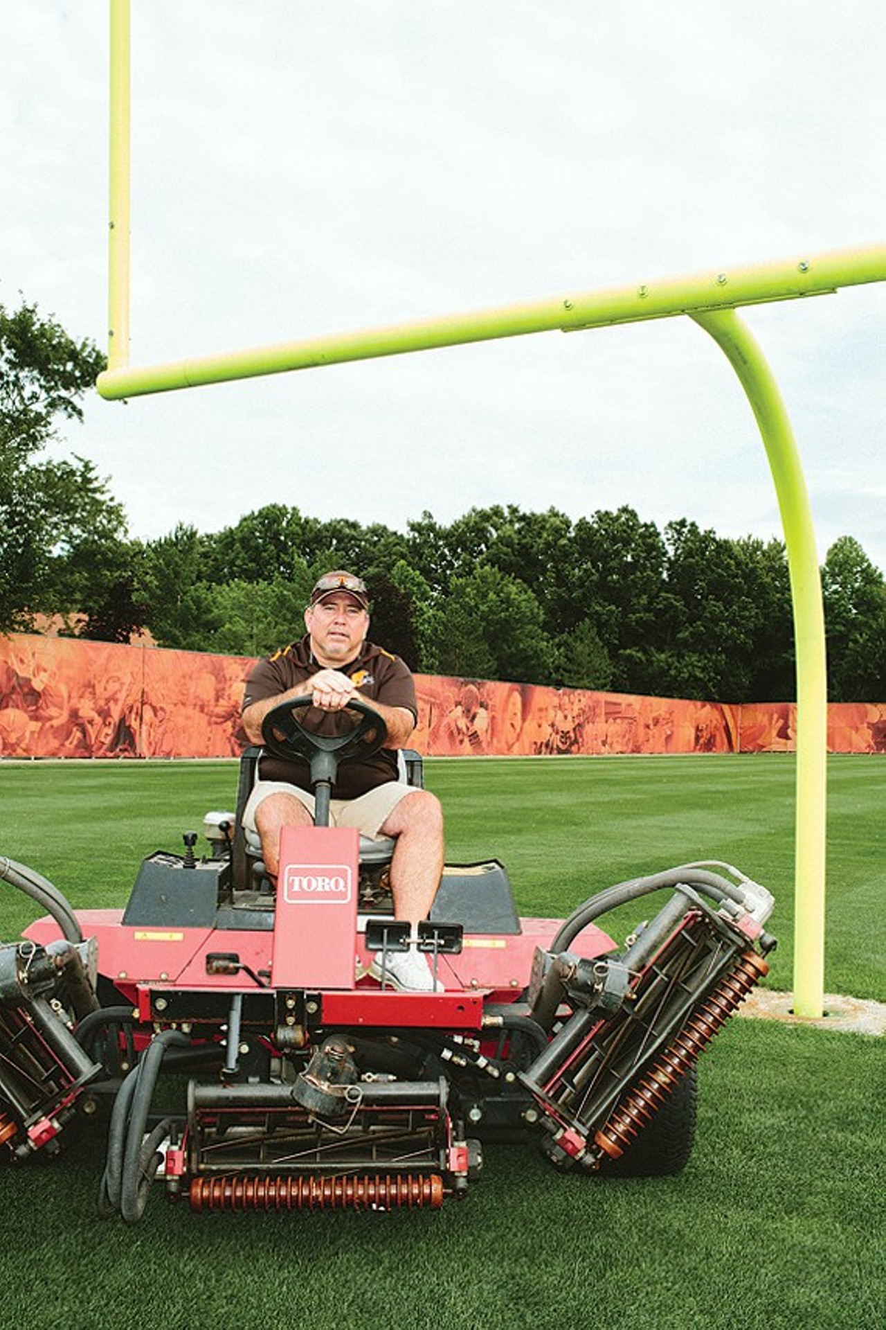 The Grass Man: Chris PowellHead Groundskeeper, Cleveland Browns
There's a saying amongst groundskeepers to this effect: If nobody is saying anything, everything is great.
Hundreds of thousands of people tune into Browns' games each fall and winter, and while they watch whatever quarterback has been left holding the hot potato at the time, they are also watching Chris Powell's handiwork. But they're not talking about it.
Powell, 47, is the head groundskeeper for the Cleveland Browns and has been since 1999. That means he's the man in charge of the turf down at the stadium as well as all the turf at the team's practice facilities in Berea.
"At both locations, I basically designed the fields myself," he says. "At first, they didn't let me design the field for the stadium &#151; there was also a time crunch &#151; up to my specs. Basically, for the NFL, you take the United States Golf Association's specifications for golf greens and that's what you work with. It's pretty much sand, with a little peat. I also added 10 percent clay to the mix to help with stability at the practice facility. We didn't do that at the stadium and there were issues from the first game. There was no stability. It's thin-cut sod, and it was late June, and it was a very hot summer in 1999. We had some issues with rooting and had to resod and redo it for the next season."
Since then, however, you haven't heard so much as a peep about the playing field not being up to par. And Powell says they haven't had to do a full resod of the complete surface in seven years, though the middle of the field, prone to the most wear and tear from 300-pound bodies, does get fresh turf throughout the year.
What does it all entail? Traveling with the team and making sure any surface they set foot on has the right hardness standards, checking the weather more than a meteorologist, organizing plans for any special events that'll be hosted at the stadium and thus affect his precious sod, and dealing with fickle kickers.
"Phil Dawson's a great guy," says Powell of the departed Browns kicker. "I don't want to say we had a love-hate relationship, but ... . He had very good success in Cleveland. We had lots of conversations through the years. He'd want to know how much sand was at the top of the soil, how that changed what cleats he might wear, he'd ask about the top dressing of the field &#151; he was very in tune to everything we did."
Back when he got out of high school, Powell's dad told him to get a job for the summer. So he got the best job he could find: working at a golf course. He saved up, went to the National Guard, went to Central Missouri State and got to work on athletic fields and golf courses and network. Which is how he got hooked up with the Browns' groundskeeper back in 1992. He was in Cleveland for a year before heading to Kansas City to work with groundskeeper guru George Toma, a legend in his line of work who has been the groundskeeper or assisted with groundskeeping at every single Super Bowl since the first one in 1967.
"I learned the high intellectual end of groundskeeping from some of the people I've worked with and the old-school stuff from George Toma," Powell says. "I like to think I've come to a sort of balance." 
By: Vince Grzegorek
