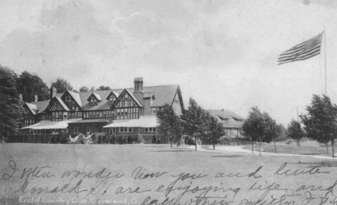 Photo shows the Tudor Revival Euclid Golf Club clubhouse which  was constructed around 1900.  A circular driveway lined with  small trees is shown to the right of the clubhouse as is a  flagpole flying the American flag.  Written at the bottom of the  front of the postcard is, "I often wonder how you and -- Donald  S. are enjoying life and each other's society.  J. G. A."  2510-2568 Derbyshire Road, Cleveland Heights, OH
The back of the postcard reads "POSTCARD;  D 1866a, The Rotograph Co., N.Y., City. (Germany);  SOL-ART PRINTS; The R CO.; Photo.  only, Copyright 1905 by the Rotograph Co."  A one cent postage  stamp is postmarked March 14, 1910.  The card is addressed to  Mrs. John Morrison in Napoleon, Ohio.